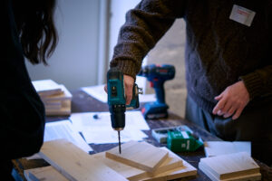 Teilnehmende des Workshops "Nisthilfenbau" bei der Arbeit mit einem Akkuschrauber.