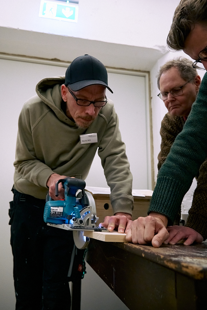 Ein Teilnehmer des Zukunftforums 2025 beim Workshop "Nisthilfenbau" bei der Arbeit mit einer Säge.